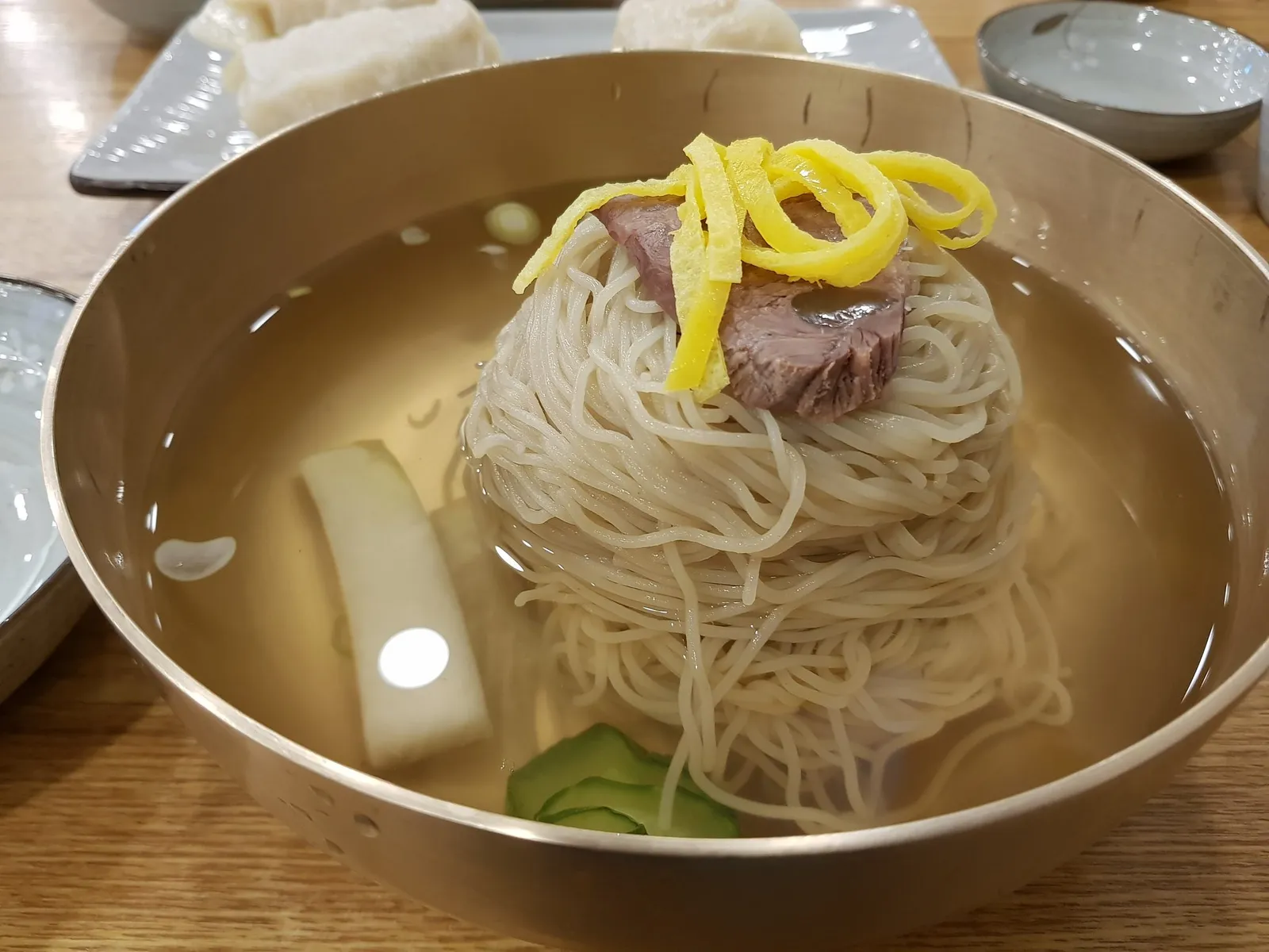 놋그릇에 정갈하게 담긴 맑은 육수의 평양냉면