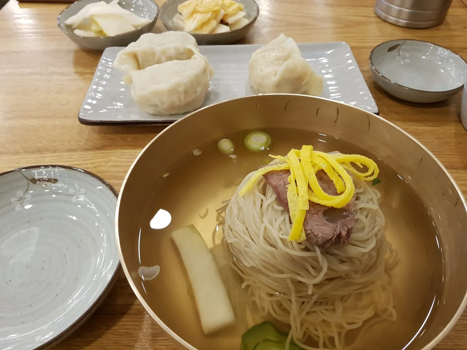 놋그릇에 담긴 평양냉면과 접시에 담긴 만두