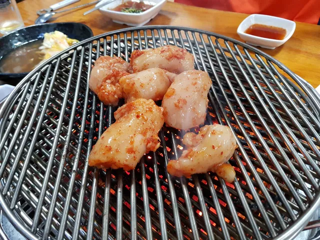 석쇠 숯불 위에 양념된 소대창을 올려 굽는 모습