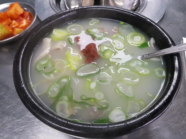 파가 듬뿍 들어가고 양념장이 올려진 뽀얀 국물의 국밥과 깍두기