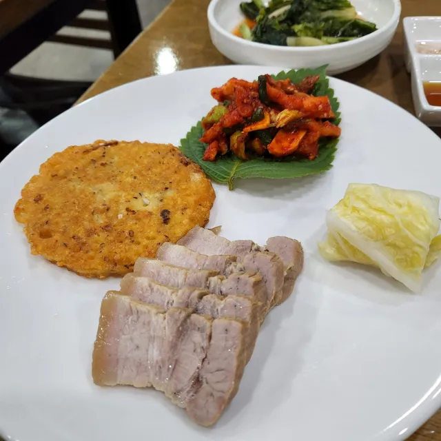 접시에 담긴 수육(보쌈), 녹두전(빈대떡), 무말랭이 보쌈김치, 백김치