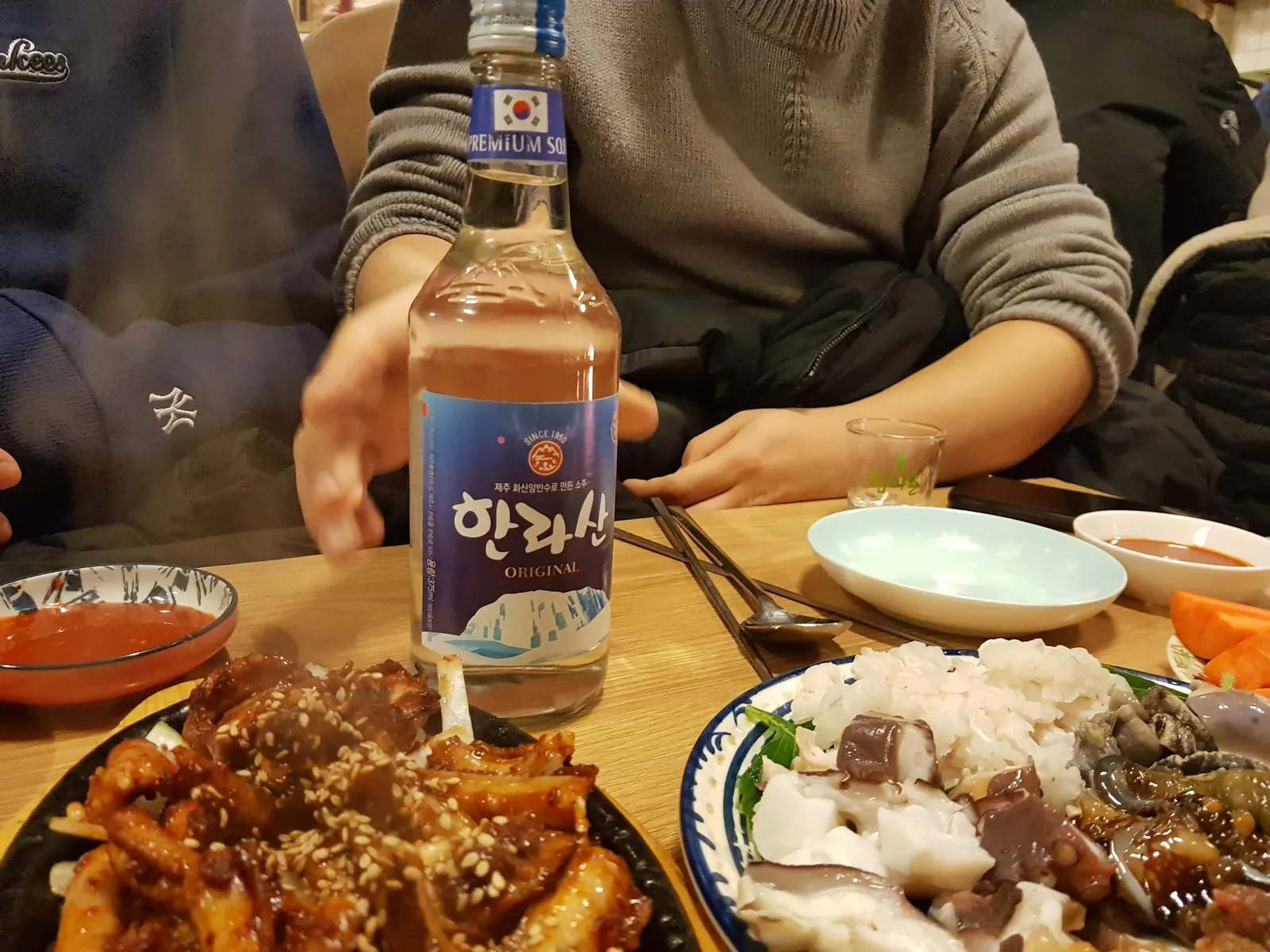 한라산 소주와 함께 차려진 문어숙회, 해산물 모둠 및 매콤한 볶음 안주