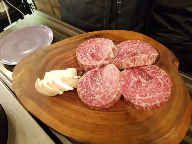 나무 도마 위에 소금이 뿌려진 두툼한 소고기 등심 또는 안심과 버섯이 담겨 있는 모습