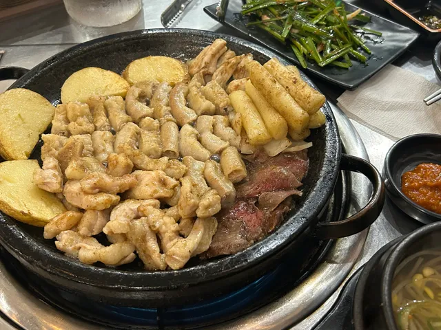 불판 위에 감자, 떡, 염통과 함께 노릇하게 구워지고 있는 소곱창구이