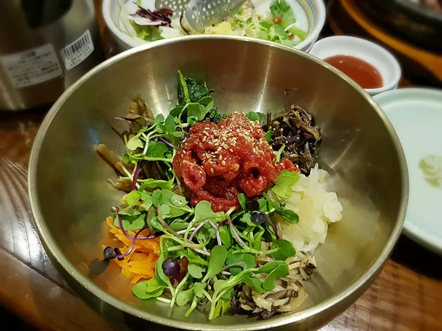 놋그릇에 육회와 신선한 각종 나물, 채소가 정갈하게 담긴 육회비빔밥