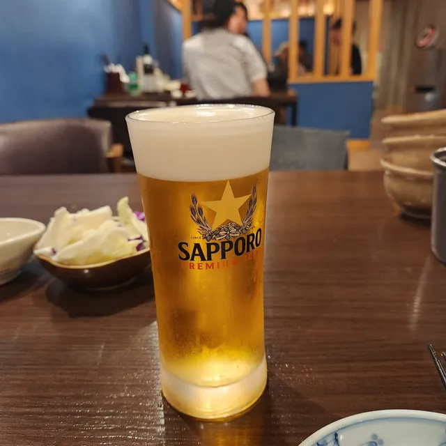 삿포로 맥주 전용잔에 담긴 시원한 생맥주와 기본 안주 양배추