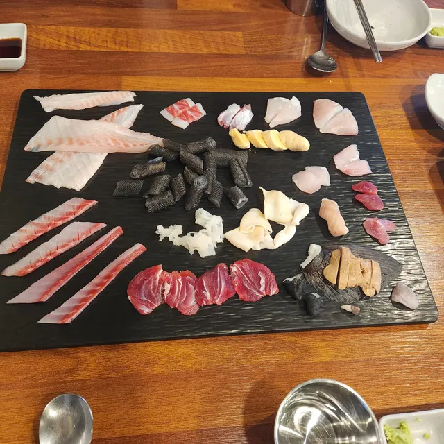 검은색 플레이트에 정갈하게 담겨 나온 다양한 부위의 민어회 및 생선회 모둠