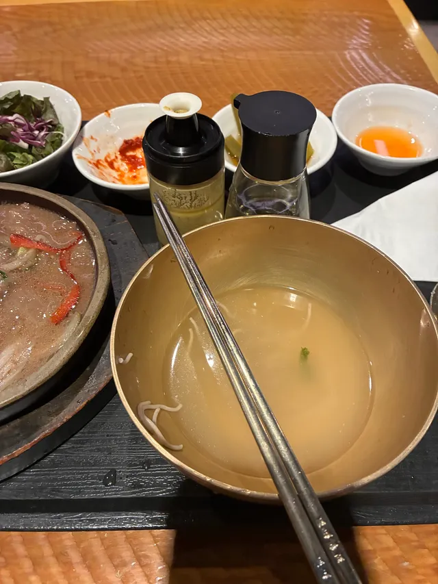 놋그릇에 담긴 국물과 철판 불고기 등의 음식을 먹고 난 상차림 모습