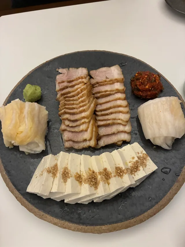 접시에 정갈하게 담긴 수육과 두부, 백김치, 무말랭이무침(보쌈김치)