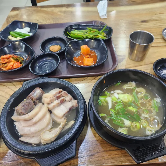 뚝배기에 담긴 수육, 순대와 국물, 밑반찬이 차려진 국밥 정식 차림