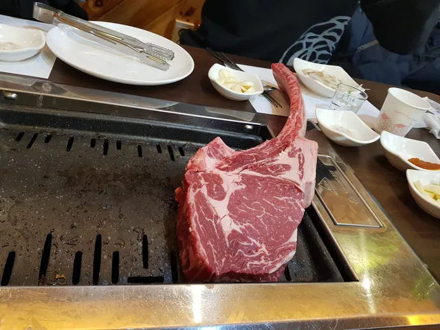 불판 위에 큼직한 토마호크 스테이크 고기가 올라가 있는 모습