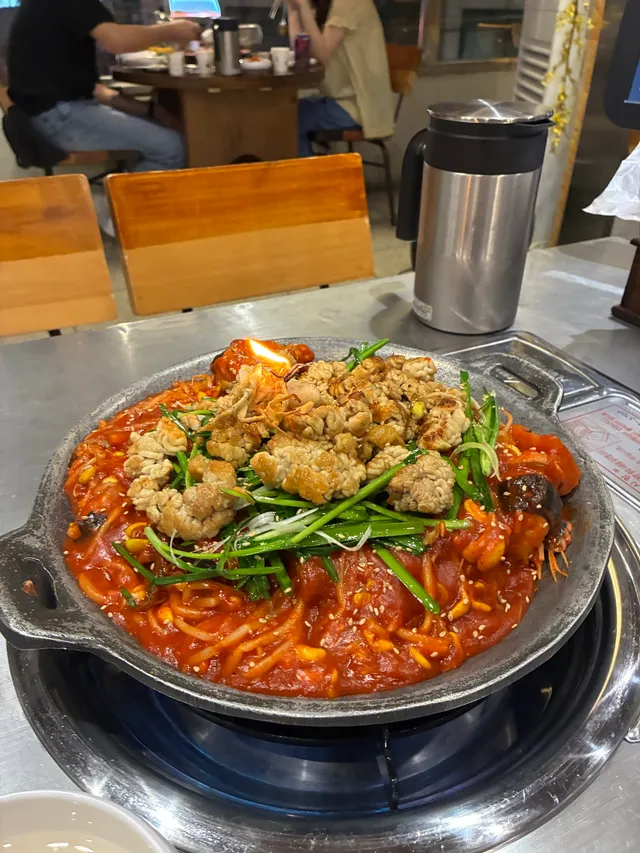 철판 냄비에 곤이와 미나리, 해물이 푸짐하게 올려진 아귀찜 또는 해물찜