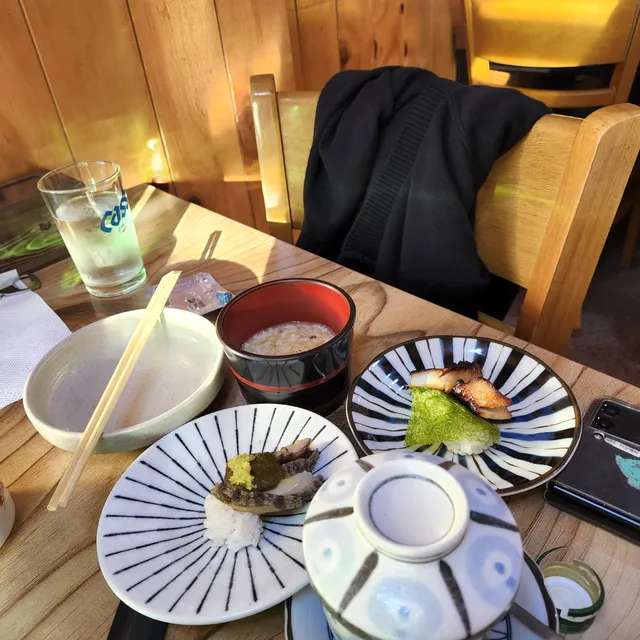 일식 코스 또는 오마카세에서 제공되는 죽, 전복초밥, 장어초밥 등이 차려진 테이블