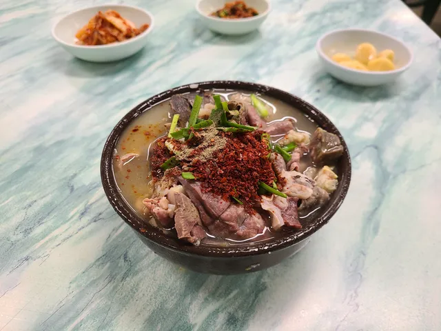 다양한 내장과 고기가 푸짐하게 올라가고 고춧가루, 후추, 다진 파가 얹어진 국밥