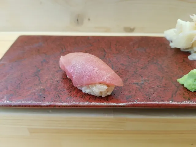 붉은색 접시 위에 놓인 참치 초밥 한 점