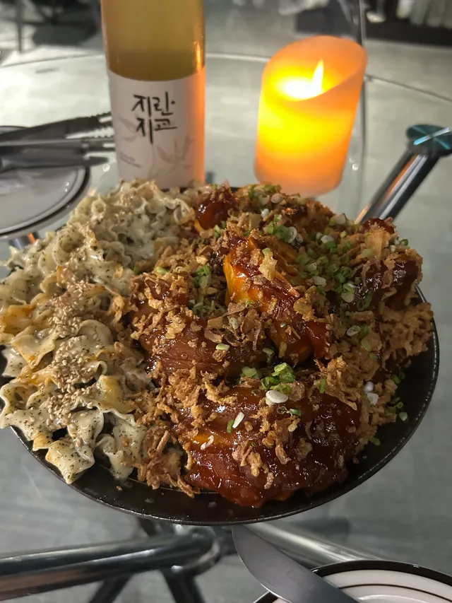 은은한 촛불 조명 아래 들기름 파스타와 양념 족발 구이가 차려진 한 상