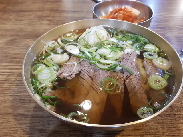 놋그릇에 담긴 맑은 국물의 곰탕과 깍두기