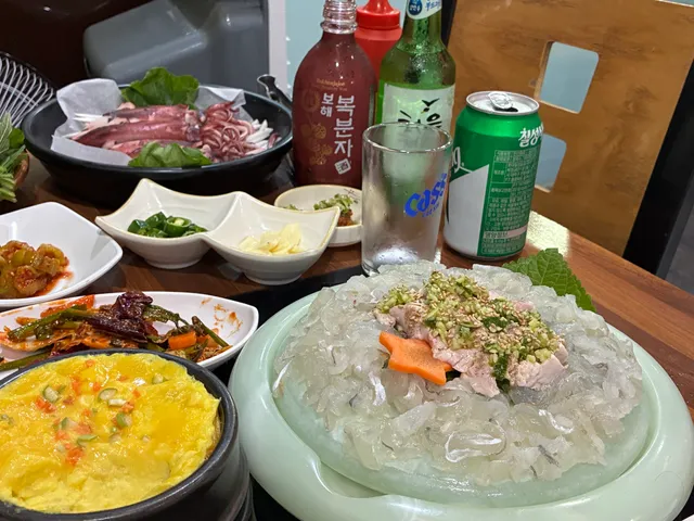 생선회와 통오징어찜, 계란찜, 주류 등이 차려진 푸짐한 해산물 상차림