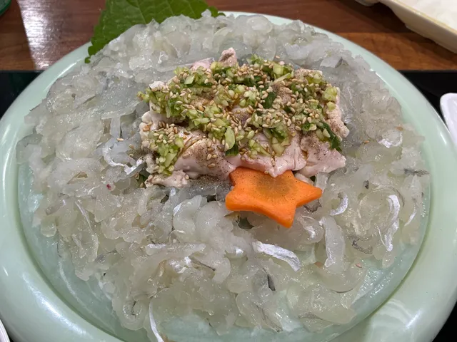 접시에 푸짐하게 담긴 복어회 또는 쥐치회와 위에 얹어진 생선 간