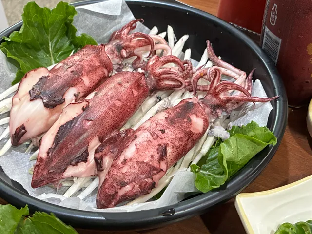접시 위에 무채와 상추를 깔고 올려진 통오징어찜 세 마리
