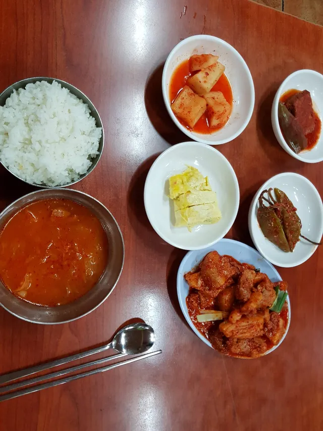 공깃밥, 국, 제육볶음 및 계란말이, 깍두기 등 반찬이 차려진 백반 한 상차림