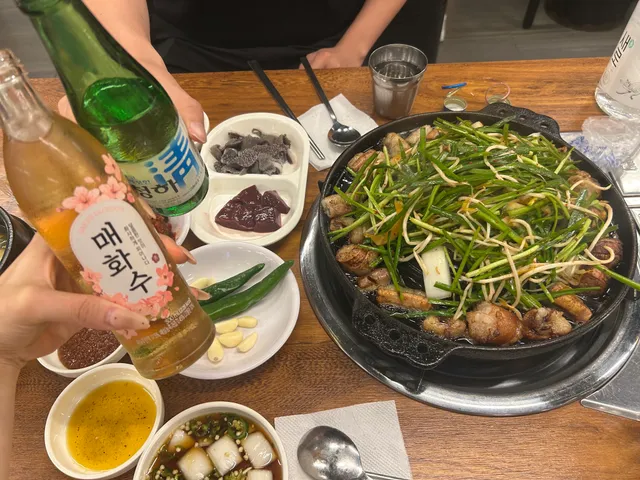 불판에 구워지는 소곱창구이와 부추, 생간과 천엽, 매화수와 청하가 차려진 식탁