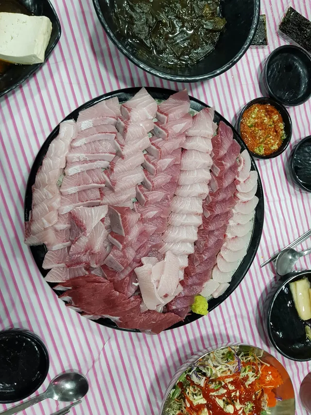 접시에 푸짐하게 썰려 나온 방어회와 다양한 기본 반찬