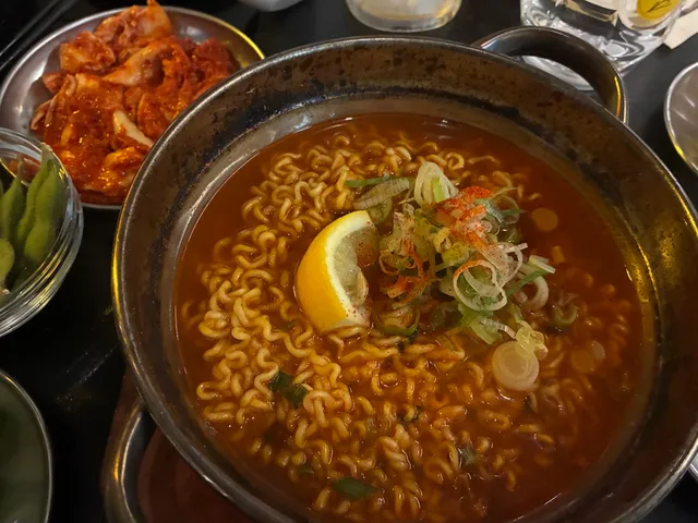 냄비에 담긴 얼큰한 라면과 김치, 완두콩 반찬