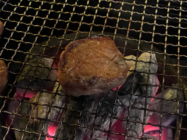 숯불 위 석쇠에서 노릇하게 구워지고 있는 두툼한 소고기 구이