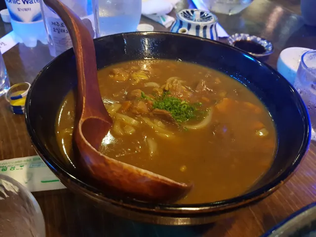 큰 그릇에 담긴 카레우동과 나무 국자