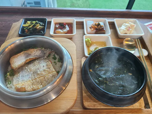은색 솥에 구운 생선이 올라간 솥밥 정식과 미역국, 다양한 반찬 상차림